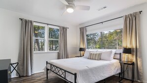 A bedroom with a bed, two bedside tables with lamps, a ceiling fan, and a window with curtains. - LAKEFRONT Bliss FLAT to water: Spacious home with Game Room, Sleeps 15 Guests!  (Garfield)