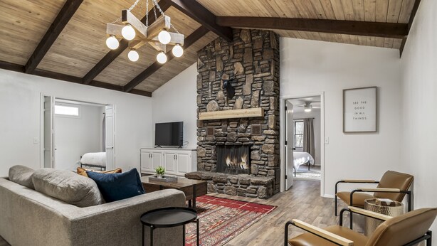 A spacious living room with a stone fireplace, a sofa, a coffee table, and leather chairs. - LAKEFRONT Bliss FLAT to water: Spacious home with Game Room, Sleeps 15 Guests!  (Garfield)