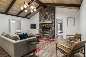 A spacious living room with a stone fireplace, a sofa, a coffee table, and leather chairs.