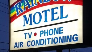 A motel sign with the name "Rainbow Motel" and mentions amenities like TV, phone, and air conditioning.