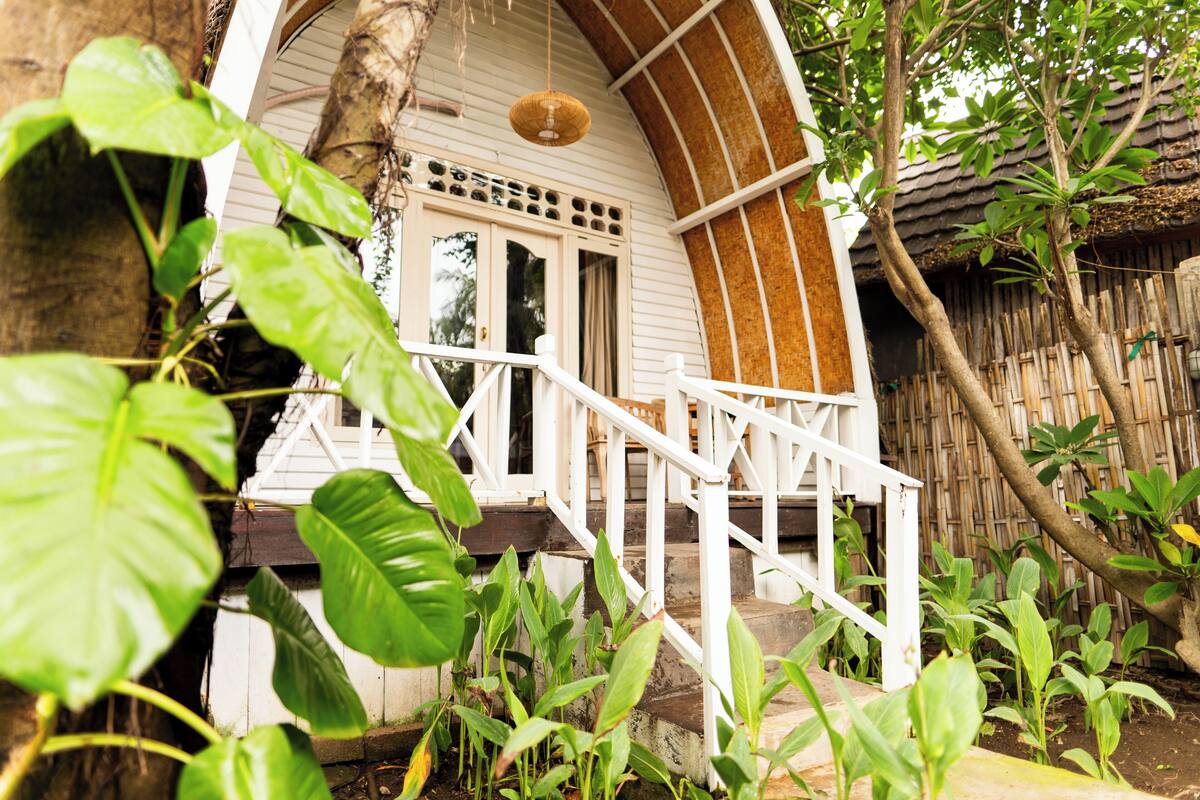 A house with a white exterior, a wooden staircase, and a porch with a white railing.