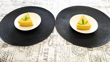 Two black woven placemats with a slice of yellow cake on top, placed on a table with vintage-style paper background.