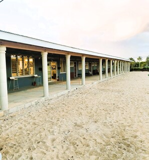 A beachside building with a covered patio area, columns, and a sandy beach in the foreground. - Toafa Lodge (Eua)