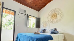 A bedroom with a wooden ceiling, a bed with a blue and white bedspread, two air conditioning units, and a decorative wall piece. - Carpe Diem (Cairu)