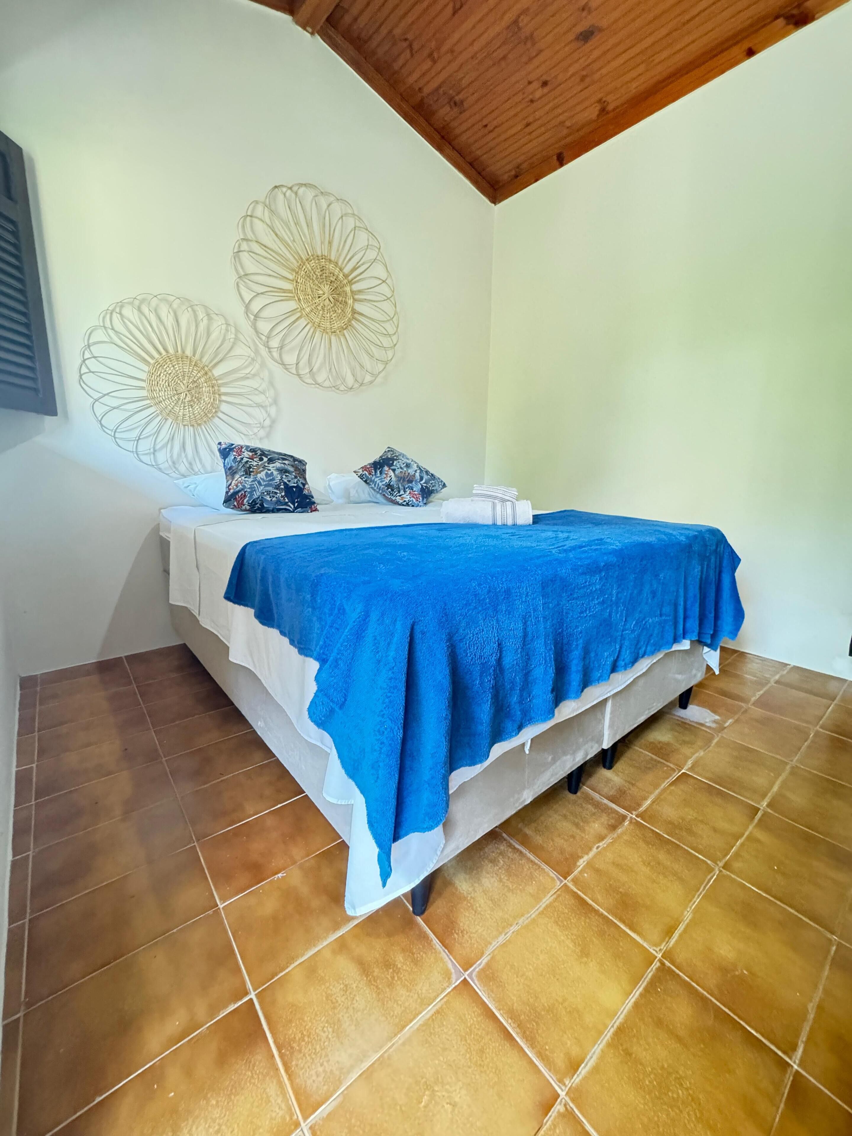 Un dormitorio con una cama, una manta azul y decoración en la pared.