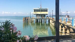 En brygga med en liten byggnad som har skylten ”NAVIGAZIONE Lago Trasimeno”, och som sträcker sig ut i vattnet.