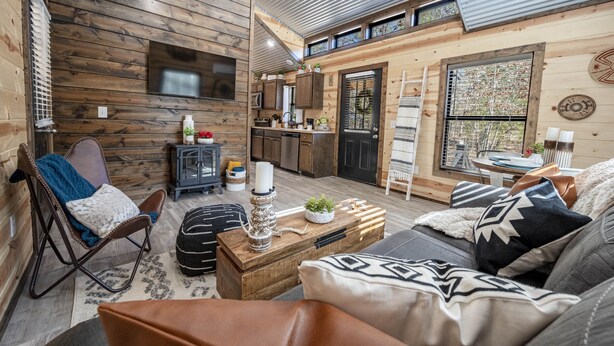 Un interior de cabaña acogedor, con sala de estar, mesa de comedor y cocina.