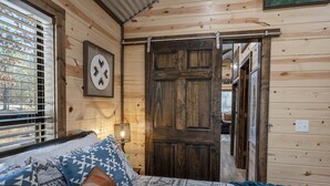 Una habitación acogedora de madera con una cama, un cuadro en la pared y una puerta.