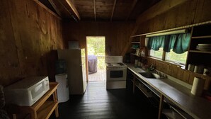 Een kleine keuken met houten wanden en een raam met uitzicht op een terras.