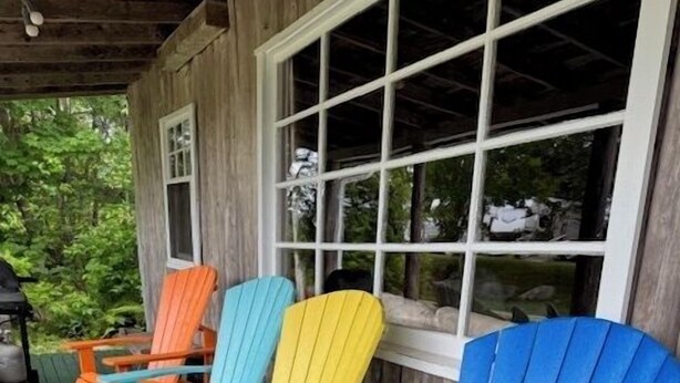 Een veranda met kleurrijke Adirondack-stoelen en een houten terras.