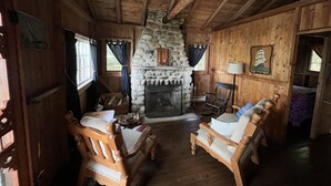 Un intérieur de chalet chaleureux avec une cheminée en pierre, des meubles en bois et une décoration rustique.