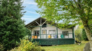 A cabin with a porch, surrounded by trees and a grassy area. - Beach Cottage - Whispering Firs - Hubbards Beach (Hubbards)