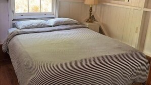 A bedroom with a bed, a window, a lamp, and a picture on the wall. - Beach Cottage - Whispering Firs - Hubbards Beach (Hubbards)