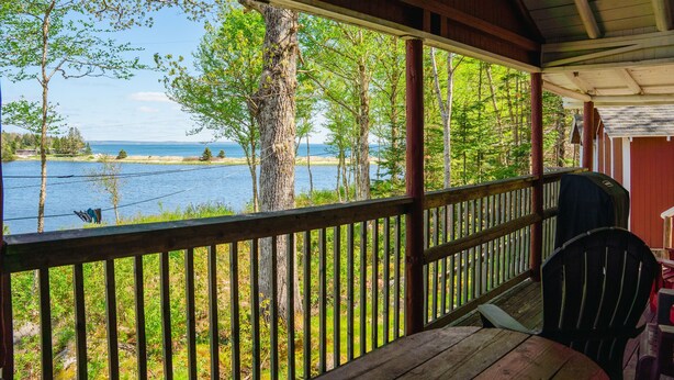 A wooden deck with a view of a lake and trees.