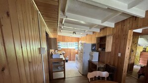 Ein Holzinnenraum mit Küchenzeile, inklusive Kühlschrank, Mikrowelle und Holzschränken.