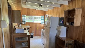 Eine kleine Küche mit Holzwänden, einem Kühlschrank, einer Mikrowelle und einem Spülbecken.