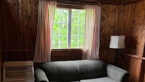 A cozy room with a wooden ceiling, a sofa, a small table, and a window with curtains. - Beach Cottage - Pine Terrace - Hubbards Beach (Hubbards)