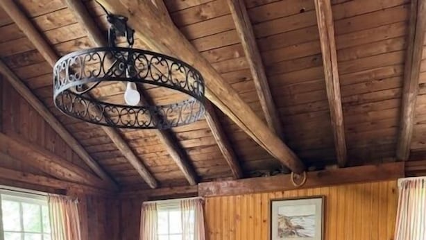 A cozy room with wooden walls, a stone fireplace, a leather sofa, and a patterned armchair. - Beach Cottage - Pine Terrace - Hubbards Beach (Hubbards)