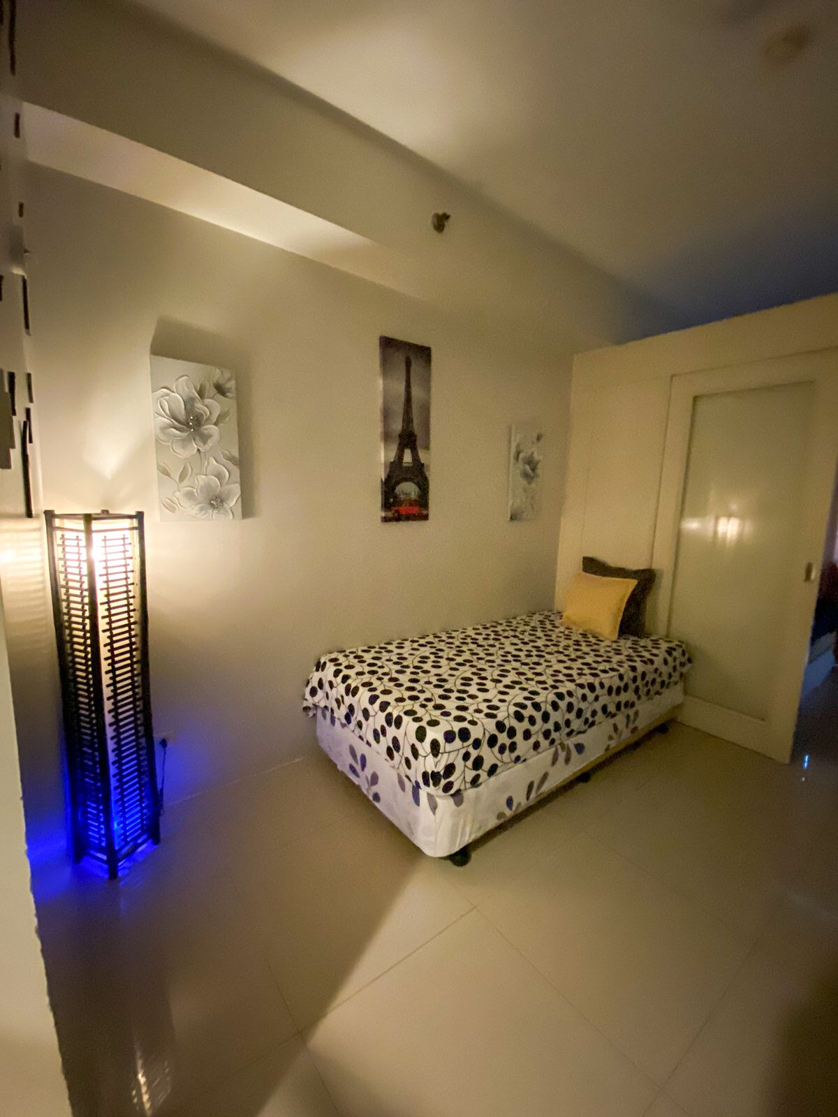 A bedroom with a bed, a door, and wall art including a picture of the Eiffel Tower.