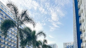 A modern urban street with high-rise buildings, palm trees, and a clean sidewalk. - Madison Place at Sea Residences powered by Cocotel (Pasay)