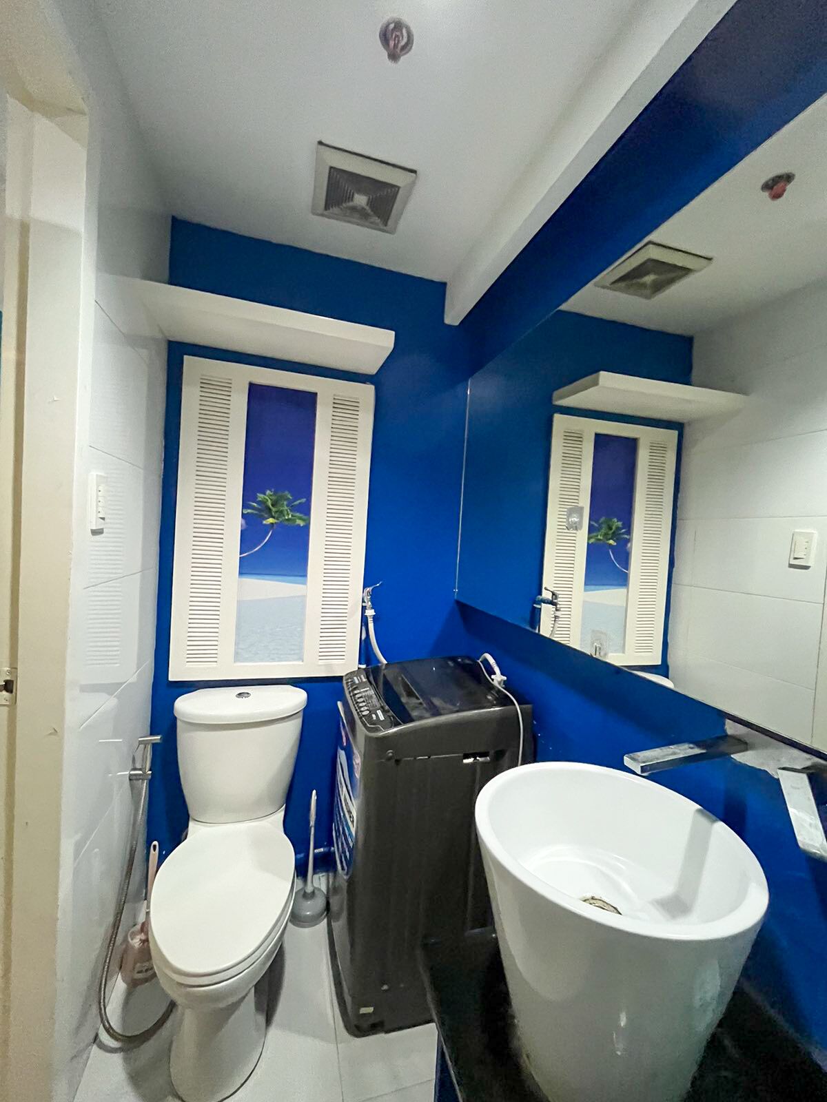 A bathroom with two toilets, a large sink, and a mirror.