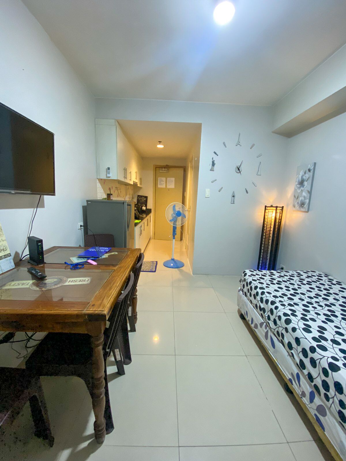 A compact living space with a dining area, a bed, a TV, and a fan.