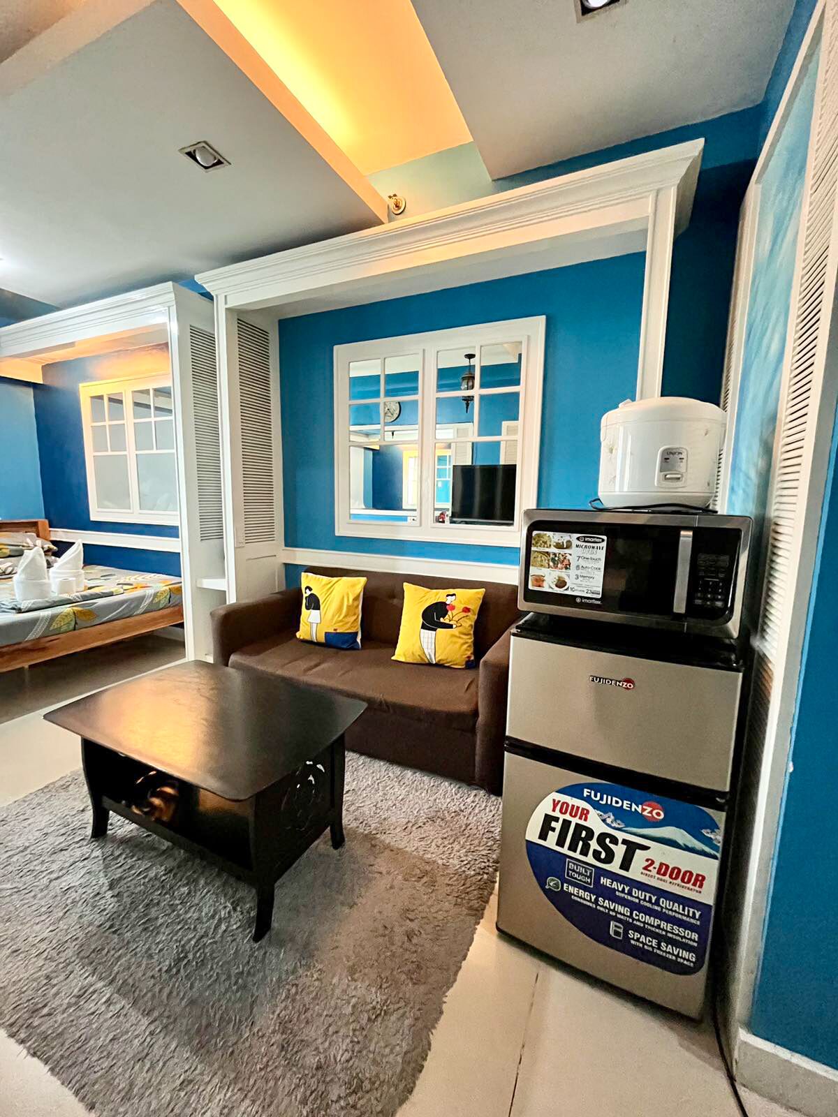 Un espace de vie compact comprenant un canapé, une table basse et un petit réfrigérateur.