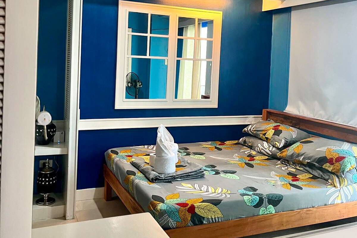A bedroom with a bed, a window, a bedside table, and a nightstand.