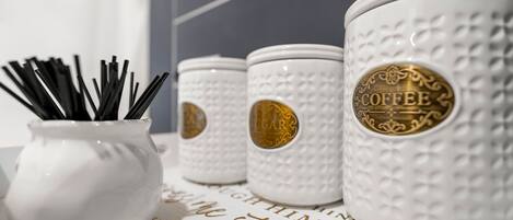 Drie witte keramische koffiemokken met reliëfpatronen en gouden accenten, geplaatst op een oppervlak met een decoratief lettertype.