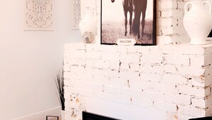 Una chimenea de ladrillo blanco con un cuadro enmarcado de un caballo, paneles decorativos en la pared y un diseño de chimenea moderno.