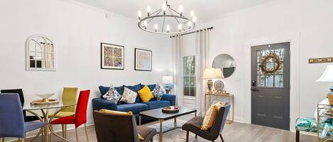 A modern living room with a blue sofa, a coffee table, and a chandelier.