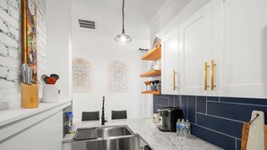 Una cocina moderna con armarios blancos, un lavamanos de acero inoxidable y una encimera de granito.