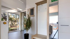 Ein modernes Interieur mit einem großen Fenster, einer Topfpflanze und einer hölzernen Bank.