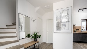 Ein modernes Interieur mit einer Treppe, einer Bank, einem Topfpflanzen und einem großen abstrakten Gemälde.