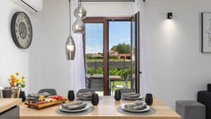 Ein Essbereich mit Holztisch, Stühlen und Blick ins Freie durch eine Glastür.