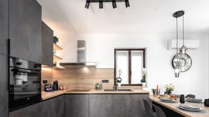 Eine moderne Küche mit Einbauofen, Edelstahl-Dunstabzugshaube und einer Holz Arbeitsplatte.