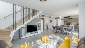 Un salon moderne avec un escalier, un coin repas et une cuisine.