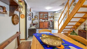 Ein Essbereich mit einem Holztisch, einer Messing-Schüssel und einer Treppe, die in eine obere Ebene führt.