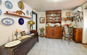 A traditional kitchen with a wooden counter, a gramophone, and various decorative plates on the wall.