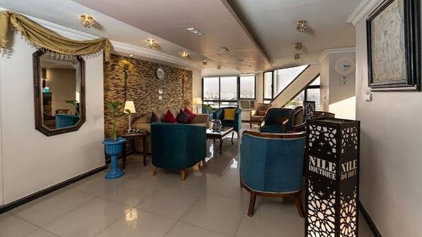 Un amplio salón con una pared de piedra, un espejo grande y una escalera que sube a un nivel superior.