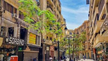 Calle con edificios, una motocicleta estacionada y un árbol.