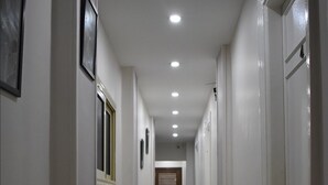 Un pasillo con suelo de mármol, paredes blancas y puertas a ambos lados.