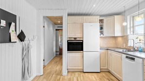 Eine moderne Küche mit hellen Holzschränken, einem weißen Kühlschrank und Holzboden.