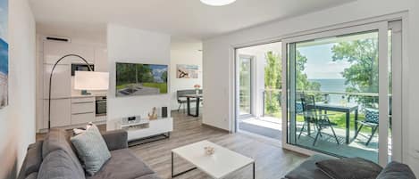 A modern living room with a sofa, coffee table, TV, and a balcony with a view.