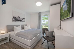 A modern bedroom with a bed, bedside tables, a desk, and a chair. - Ferienresidenz Am Haff - Neuerbautes Feriendomizil in Ruhiger Lage mit Blick auf das Stettiner Haff (Garz)