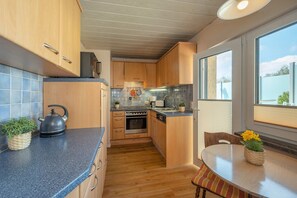 Una cocina moderna con armarios de madera, estufa y comedor con mesa y sillas.