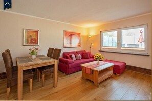 Una sala de estar amoblada con una mesa de comedor, un sofá rojo y una mesa de centro con girasoles.