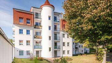 Un immeuble résidentiel à plusieurs étages, doté d’une tour cylindrique centrale, de balcons et d’une pelouse bien entretenue.