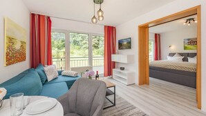A modern living room with a sofa, a dining table, and a TV. - Ferienwohnung Kranich (Heringsdorf)