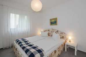Ein ordentlich eingerichtetes Schlafzimmer mit einem Bett, einem Nachttisch, einer Lampe und einem Bild an der Wand.